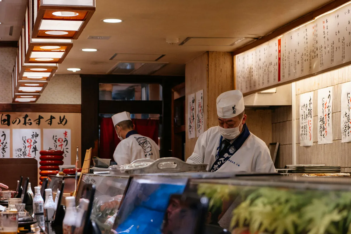 Sushi chefs preparing an omakase meal across a wooden counter.