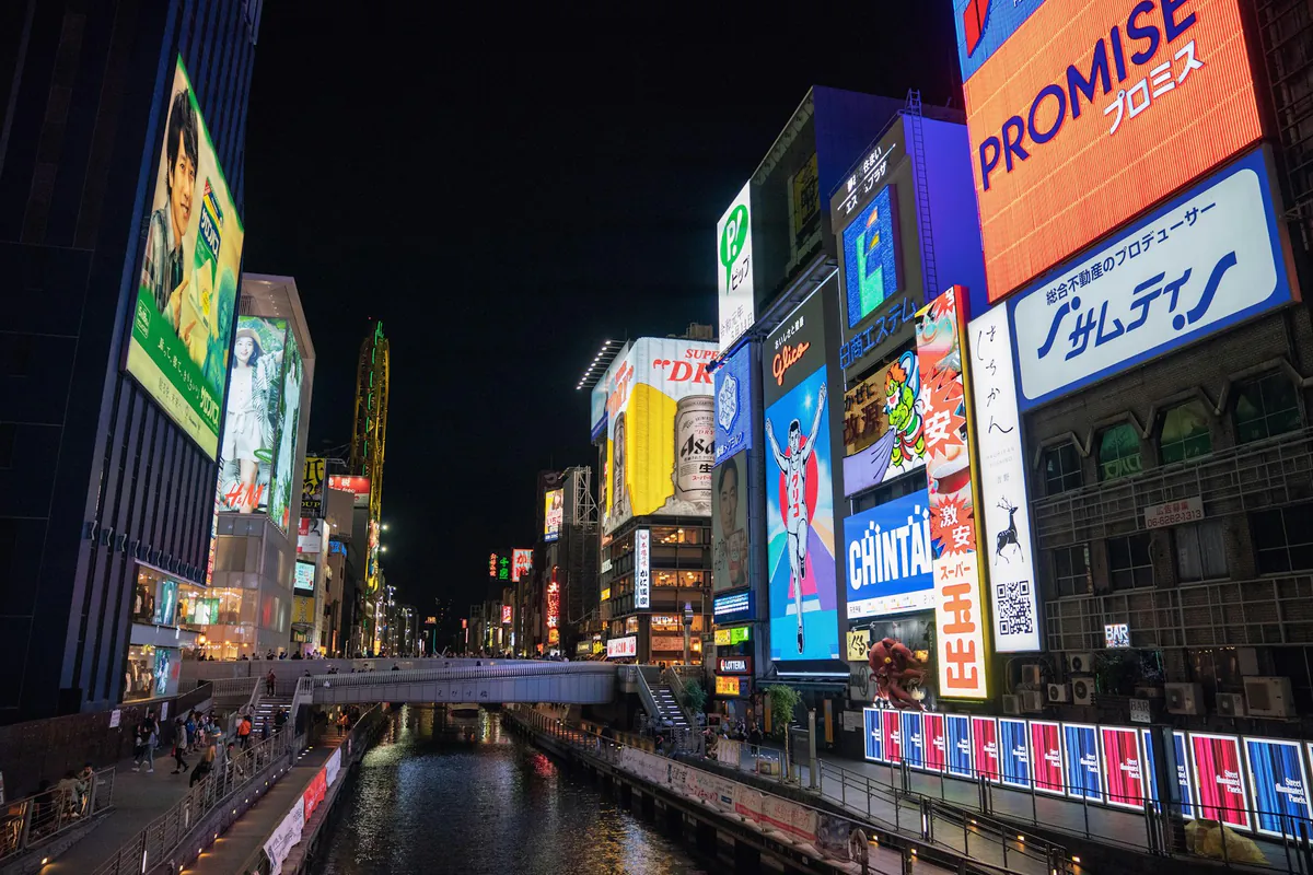 Neon billboards reflected in the Dotonbori canal at night in Osaka.