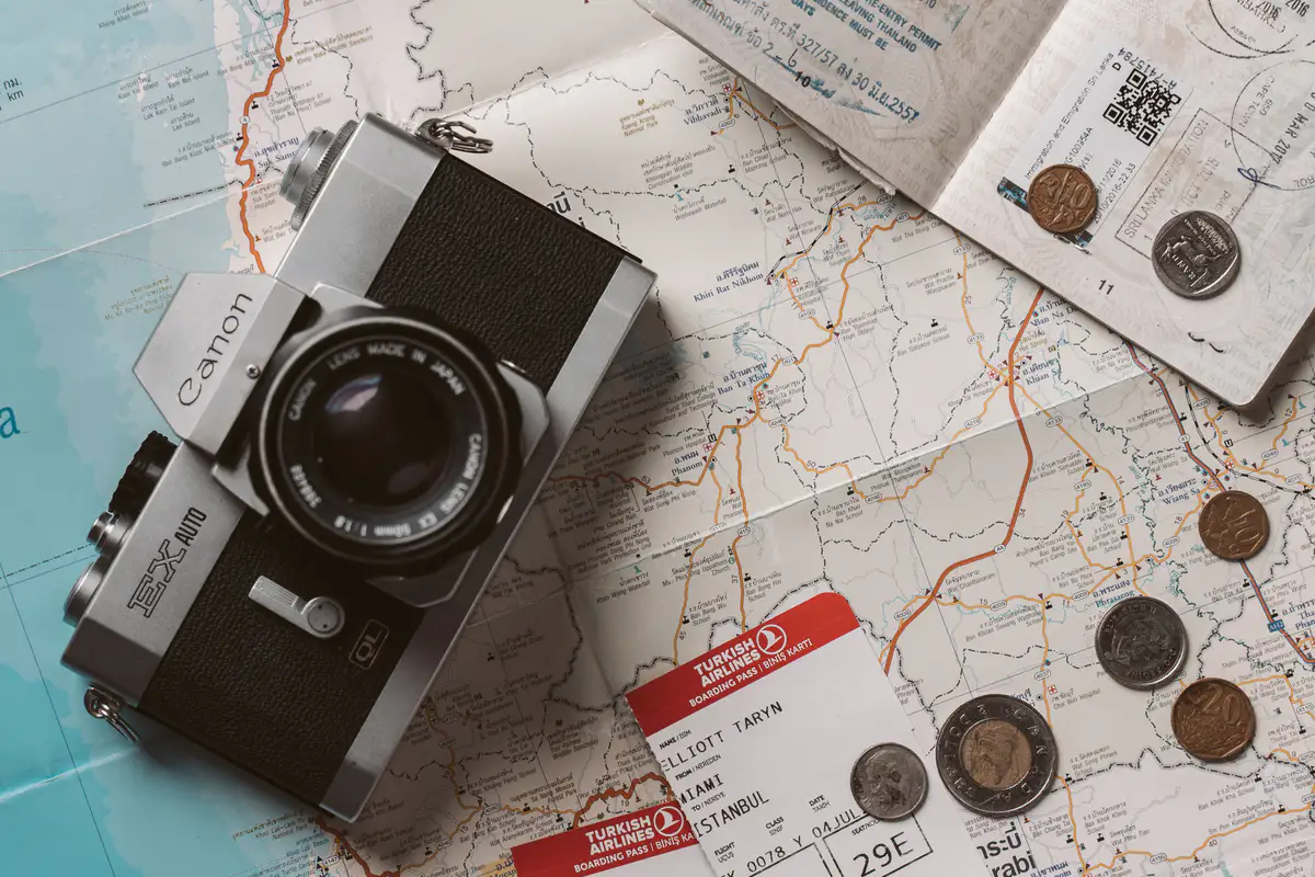 Passports and travel tickets arranged on a map beside a vintage camera.