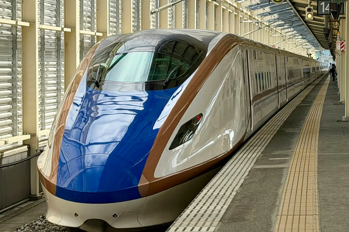 A modern shinkansen waiting at a station platform.