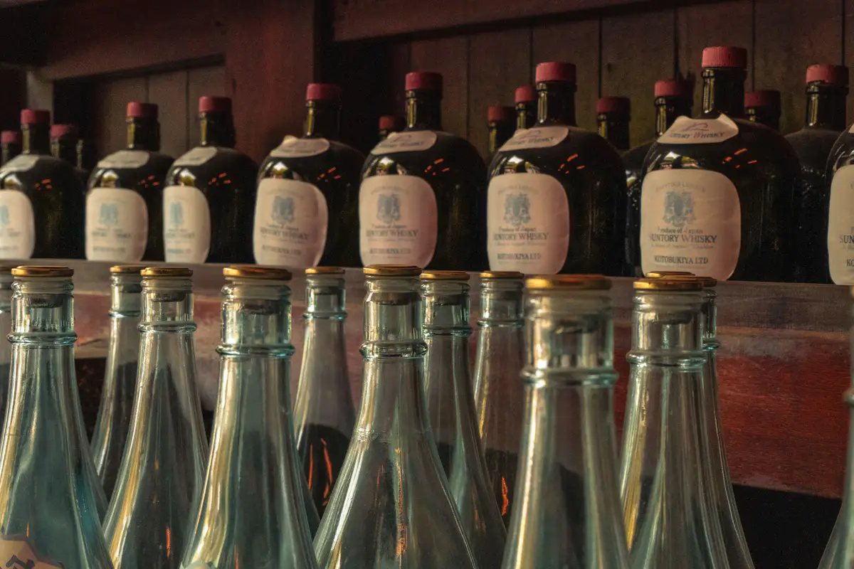 Vintage Japanese whisky bottles line the shelves of a warmly lit Tokyo bar.